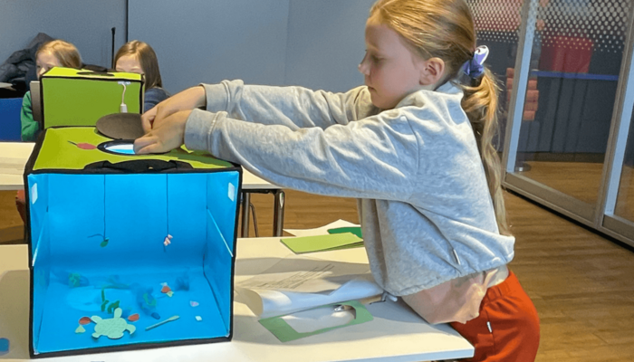 Ein Mädchen baselt ein Aquarium aus verschiedensten Materialien.