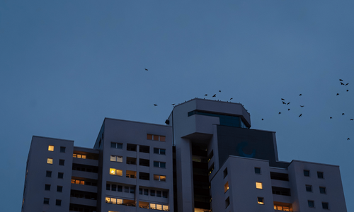 Ein Hochhaus in der Abenddämmerung mit erleuchteten Fenster.