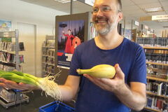 Mann hält Lauchzwiebeln und eine Banane in der Hand