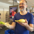 Mann hält Lauchzwiebeln und eine Banane in der Hand
