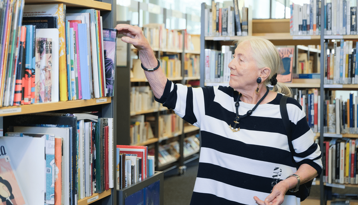 ältere Dame stöbert in der Bücherhalle