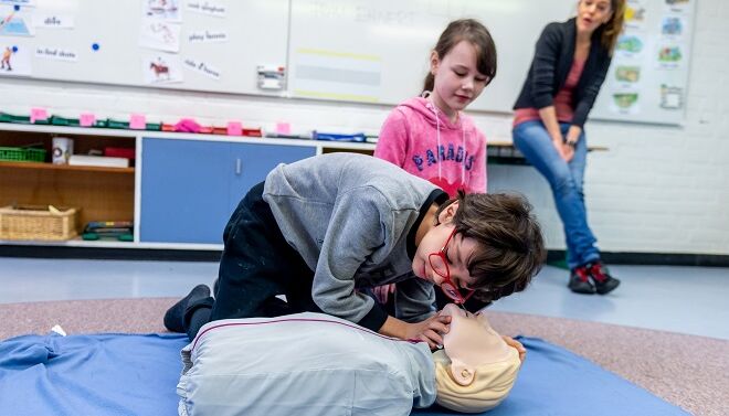 Ein Kind übt an einer Puppe erste Hilfe