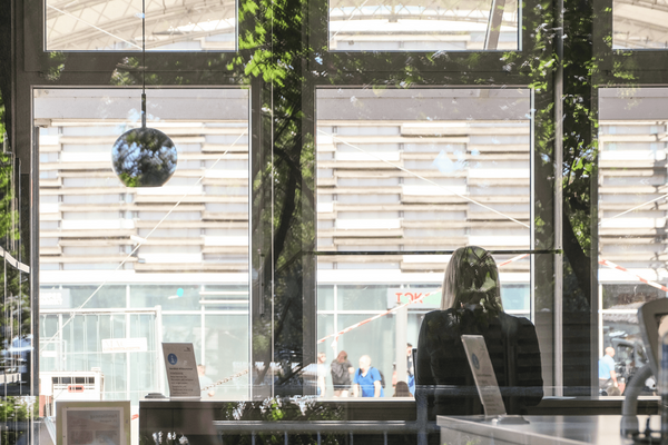 eine Person sitzt mit einem Laptop vor einem Fenster in einer Bibliothek