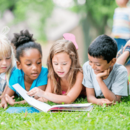 4 lesende Kinder im Gras