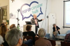Mann am Rednerpult zeigt eine Präsentation