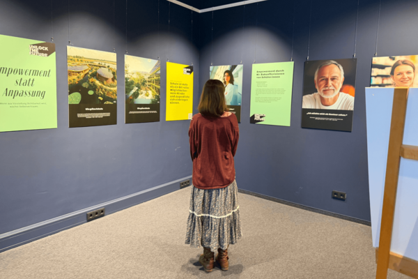 Eine Person steht vor bunten Ausstellungsplakaten