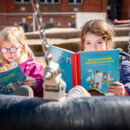 zwei Mädchen mit Buch in Schaukel