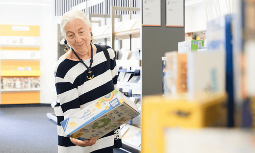 ältere Dame stöbert in der Bücherhalle