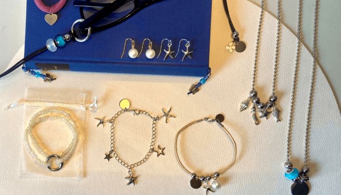 Diverse selbstgemachte Schmuckaccessoires, darunter Ohrringe, Halsketten und Armkettchen.