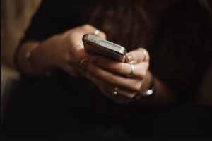 Nahaufnahme der Hände einer weiblichen Person, die ein Smartphone in ihren Händen hält.