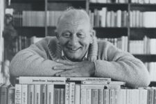 Schwarz-Weiß-Bild von James Krüss auf einem Stapel Bücher.