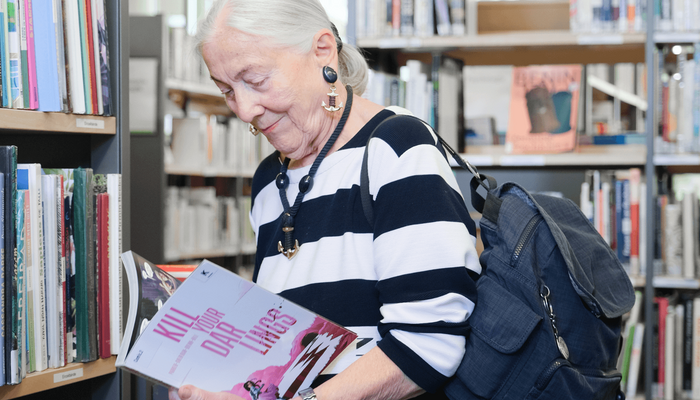 ältere Dame stöbert in der Bücherhalle