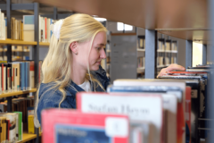 Person sucht Buch am Regal aus