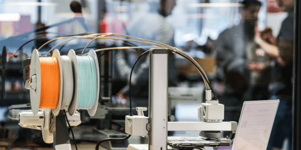 Im Vordergrund ist ein Gerät des Makerlab, im Hintergrund sind verschwommen einige Menschen zu sehen