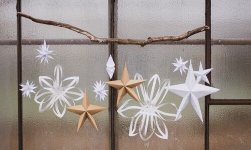 Papiersterne an einem Ast am Fenster aufgehängt