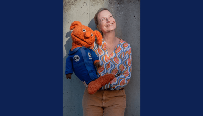 Frau mit oranger Handpuppe im Weltall-Anzug