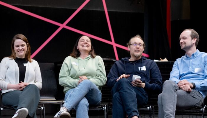 4 Personen sitzen auf eine Bühne