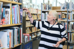 ältere Dame stöbert in der Bücherhalle