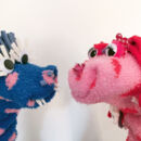 Ein blaues und ein rosa Monster, die aus Socken gebastelt sind.