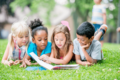 4 lesende Kinder im Gras