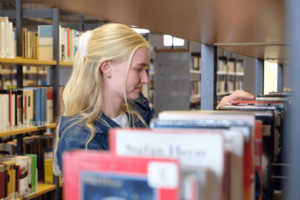 Person sucht Buch am Regal aus