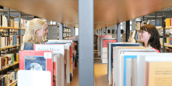 Zwei Personen stöbern Bücher in der Zentralbibliothek