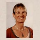 Frau im roten Oberteil vor einem neutralem Hintergrund (Silke Maddey).