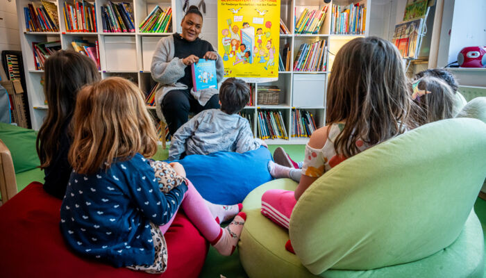 Vorlesen vor einer Kindergruppe, Bücher im Hintergrund