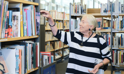 ältere Dame stöbert in der Bücherhalle