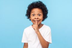 Kind, das als Zeichen zum Leisesein einen Finger an die Lippen legt