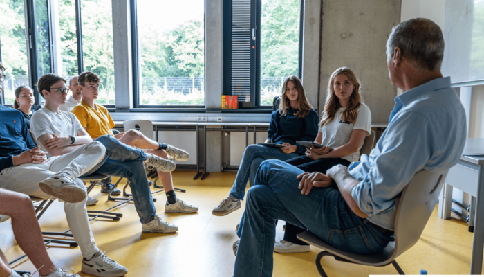 Eine Gruppe sitz im Stuhlkreis und unterhält sich.