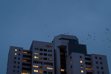 Ein Hochhaus in der Abenddämmerung mit erleuchteten Fenster.