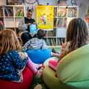 Vorlesen vor einer Kindergruppe, Bücher im Hintergrund