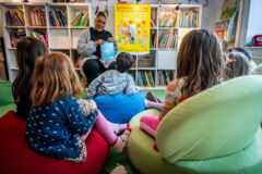 Vorlesen vor einer Kindergruppe, Bücher im Hintergrund