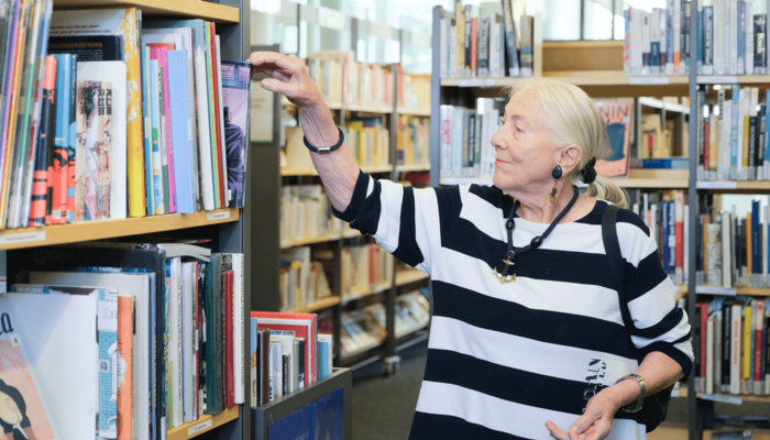 ältere Dame stöbert in der Bücherhalle