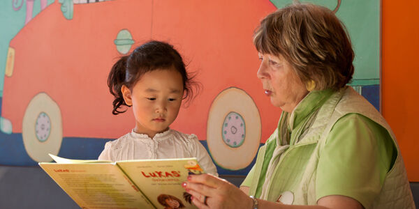 Eine Vorleserin liest Kindern ein Buch vor