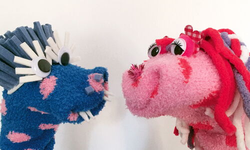 Ein blaues und ein rosa Monster, die aus Socken gebastelt sind.