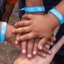 Kinderhände mit UNICEF-Armband die sich anfassen