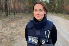 lächelnde jüngere Dame steht in Sicherheitskleidung der Presse auf einem Waldweg