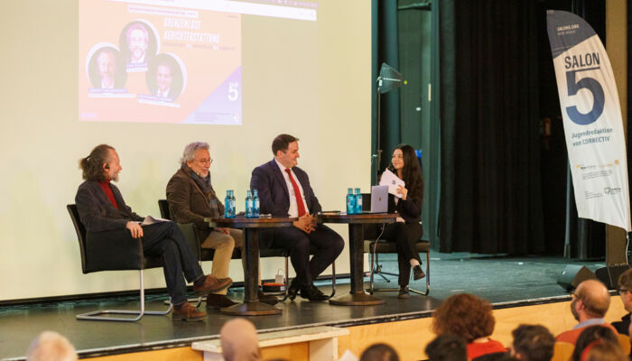 Bild zeigt 4 Menschen auf einer Bühne sitzend, die miteinander sprechen