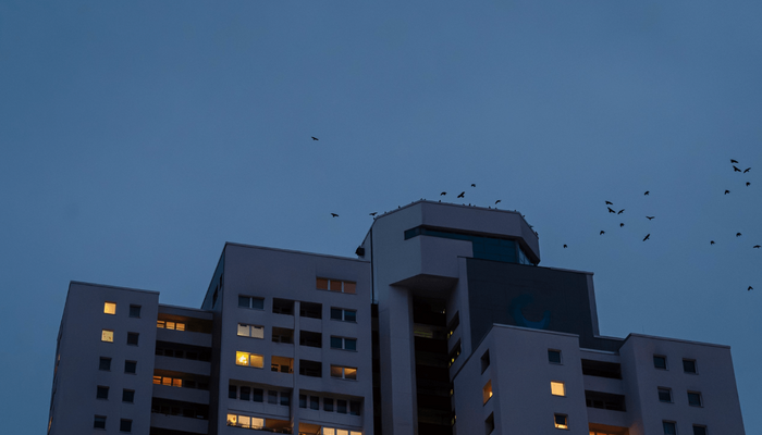 Ein Hochhaus in der Abenddämmerung mit erleuchteten Fenster.