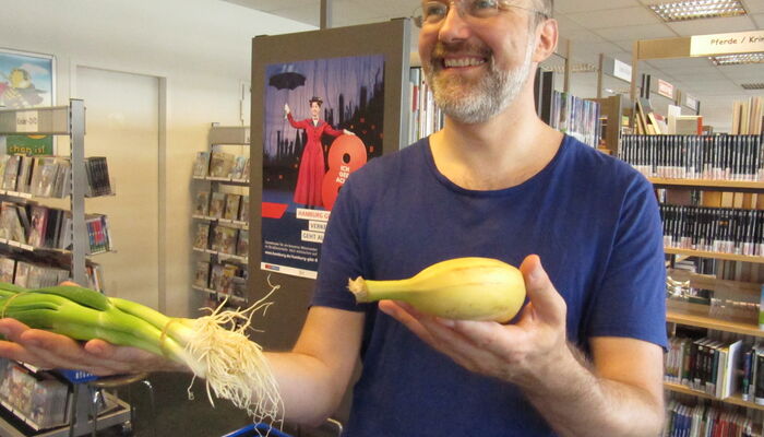 Mann hält Lauchzwiebeln und eine Banane in der Hand
