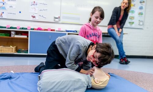 Ein Kind übt an einer Puppe erste Hilfe