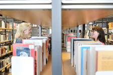 Zwei Personen stöbern Bücher in der Zentralbibliothek