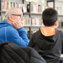 Mann hilft Kind beim Lesen lernen in der Bücherhalle