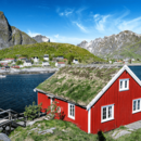 Rotes, nordisches Haus mit Bergen und Meer im Hintergrund