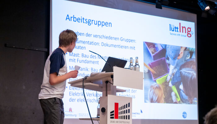 Ein Jugendlicher hält eine Lütt Ing Powerpoint-Präsentation