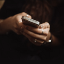 Nahaufnahme der Hände einer weiblichen Person, die ein Smartphone in ihren Händen hält.