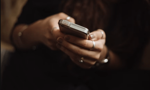 Nahaufnahme der Hände einer weiblichen Person, die ein Smartphone in ihren Händen hält.