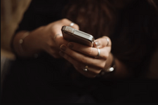 Nahaufnahme der Hände einer weiblichen Person, die ein Smartphone in ihren Händen hält.